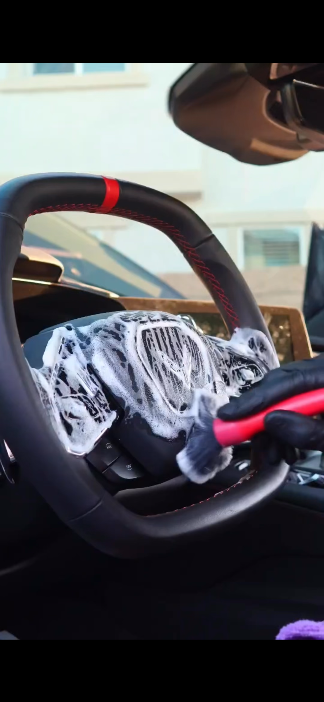 Steering wheel being cleaned with foam during interior detail